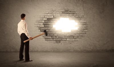 Business man hitting brick grungy wall with hammer and opening a hole-1