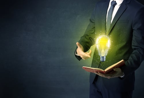 Businessman holding book with bulb.