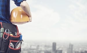 Close up of woman mechanic with yellow helmet in hand against city background.jpeg