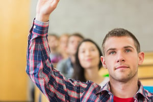 Close-up of a young male student raising hand by others in a row at the classroom.jpeg