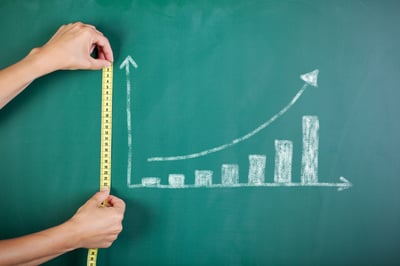 Closeup of womans hands measuring bar graph with tape on blackboard-2