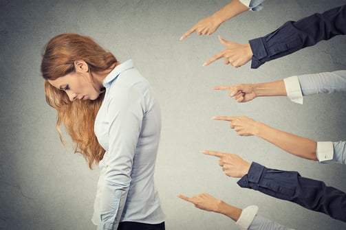 Concept of accusation guilty businesswoman person. Side profile sad upset woman looking down many fingers pointing at her isolated grey office background. Human face expression emotion feeling