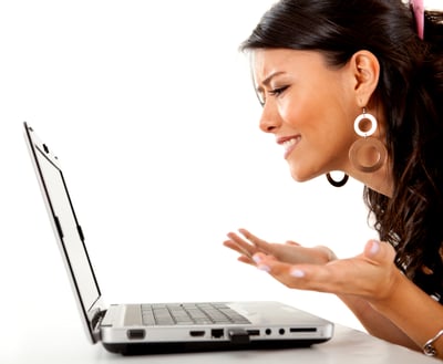 Confused woman working on a laptop computer - isolated over white