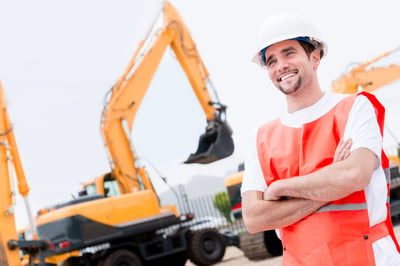 Happy man working with contruction machines and wearing helmet