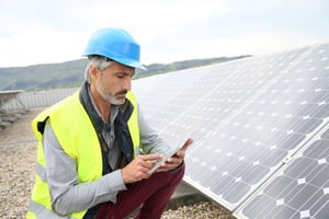 Mature engineer on building roof checking solar panels.jpeg