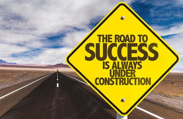 The Road to Success is Always Under Construction sign on desert road