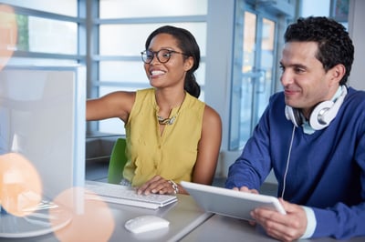 Two  colleages discussing ideas using a tablet and computer