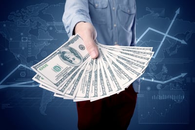 Young businessman holding large amount of bills with blue charts in the background